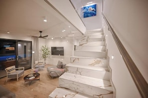A modern interior with a marble staircase, a seating area with a coffee table, and a television mounted on the wall. - Villa Vonskari (Kras)