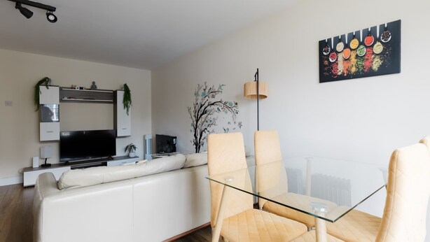 Ein modernes Wohnzimmer mit einem Glastisch, einem weißen Ledersofa und einem Flachbildfernseher.