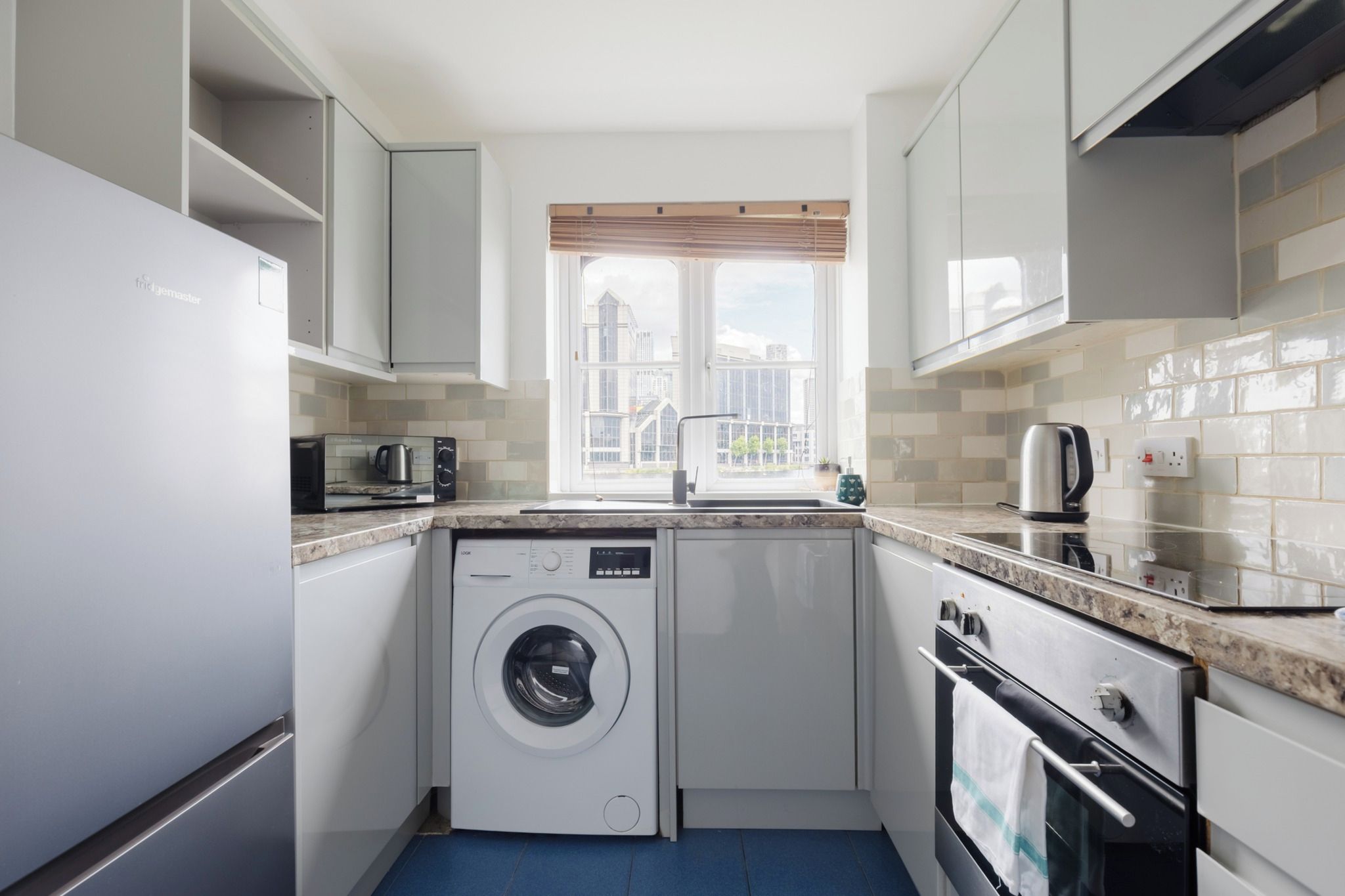 Une cuisine compacte équipée d’un lave-linge, d’une machine à café et d’une bouilloire.