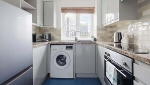 Eine kompakte Küche mit Waschmaschine, Mikrowelle und Backofen.