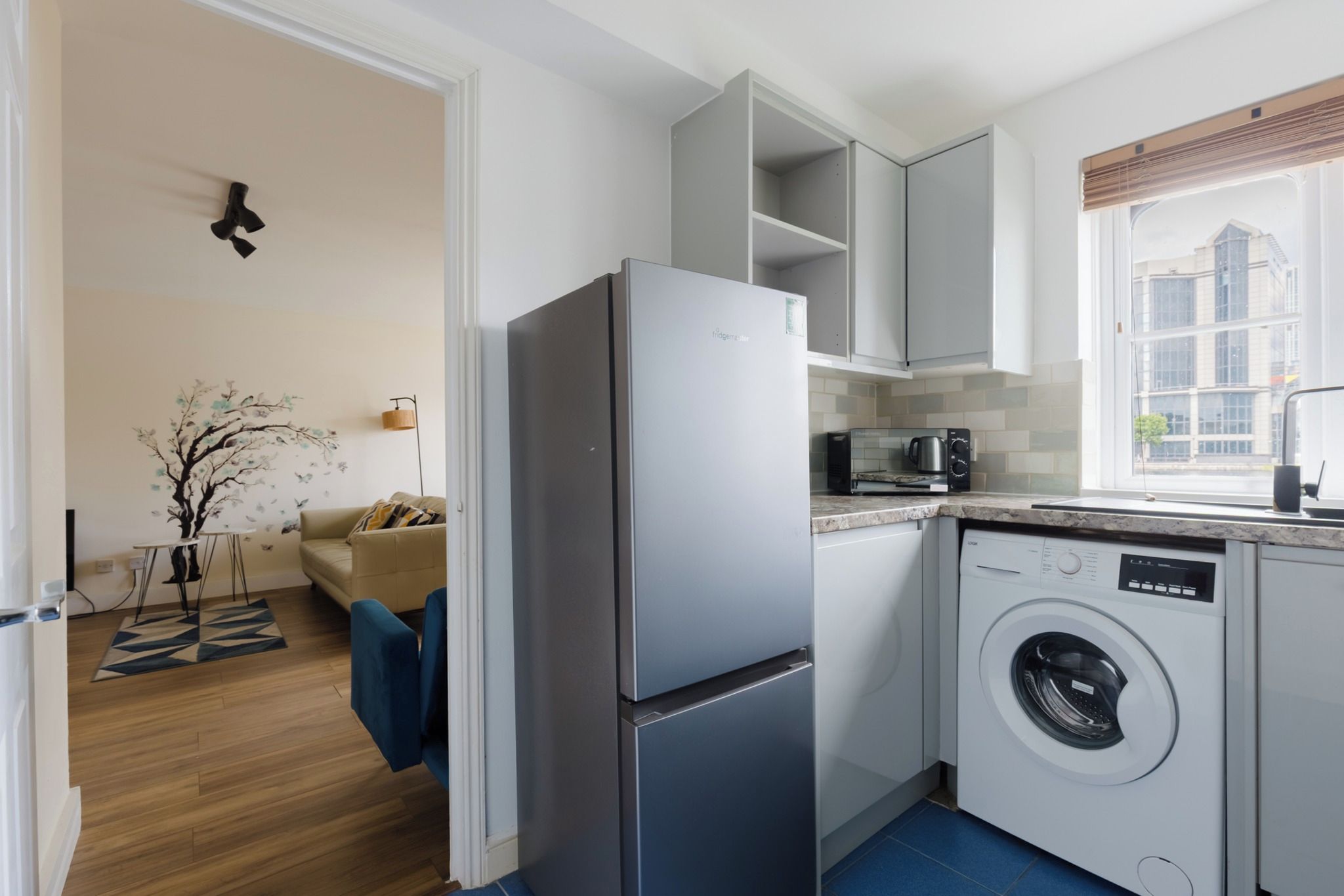 A compact kitchen with a built-in washing machine, a microwave, and a refrigerator.