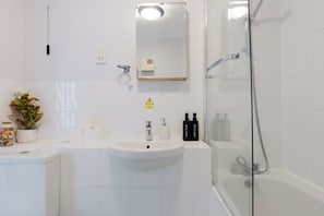 Ein modernes Badezimmer mit Waschbecken, Spiegel und Dusche in Weiß.