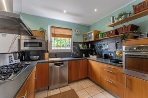 A modern kitchen with stainless steel appliances, wooden cabinets, and a window with blinds. - Quiet villa with a heated pool and gym on the Côte Bleue and in Marseille (Châteauneuf-les-Martigues)