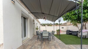 A patio with a table and chairs, a covered area, and a lawn.