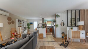 A modern living room with a sofa, a dining table, and a kitchen area.