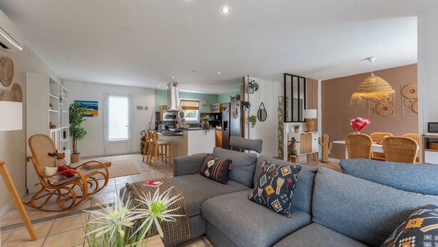 A modern living room with a sofa, a rocking chair, and a dining area with a table and chairs.