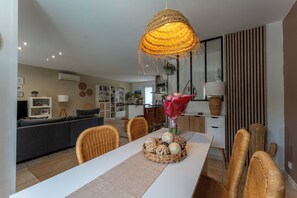 A dining area with a white table, wicker chairs, a woven light fixture, and a vase with flowers. - Quiet villa with a heated pool and gym on the Côte Bleue and in Marseille (Châteauneuf-les-Martigues)