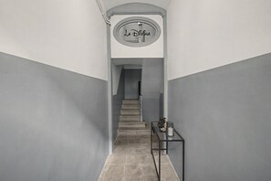 Una escalera con una mesa de vidrio y una lámpara, que lleva a un rellano con un letrero circular.