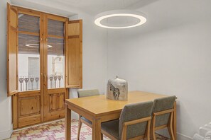 Un comedor con una mesa y sillas de madera, un jarrón decorativo y un amplio armario de madera con puertas de cristal.