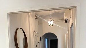 A hallway with patterned flooring, a mirror, a wooden console table, and a chair. - La Divina: Apartment with Balcony in the Heart of Figueres (Figueres)