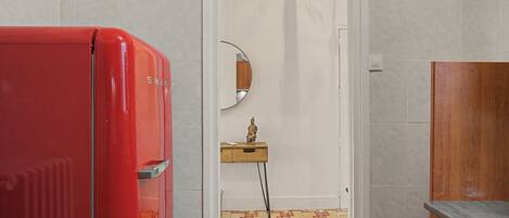 Una habitación con un refrigerador rojo, un armario de madera, un espejo y un piso con diseño.