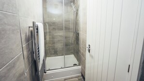 A shower with a glass door, a towel rack, and a white door. - Queensferry Collection - Residence 7 (Derby)