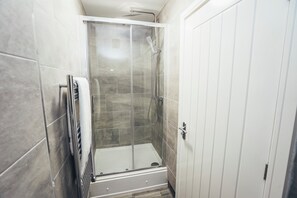 A shower with a glass door, a towel rack, and a white door. - Queensferry Collection - Residence 7 (Derby)