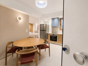 Eine moderne Küche mit Kühlschrank, Backofen und Schränken. Ein Essbereich mit rundem Tisch und Stühlen ist ebenfalls vorhanden.