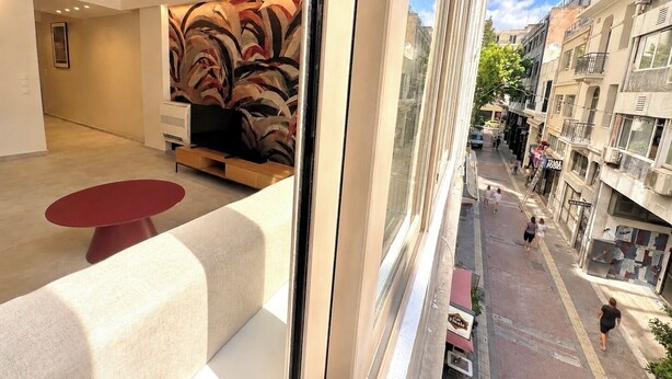 Un interior moderno con un sofá, una mesa roja y una pared con diseño.