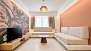 Una sala de estar moderna con un televisor de pantalla plana, un mueble de entretenimiento de madera, un sofá color beige, una mesa de centro redonda y un cuadro abstracto grande en la pared.