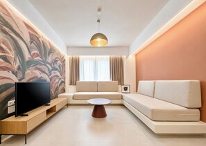 A modern living room with a flat-screen TV, a wooden entertainment unit, a beige sofa, a round coffee table, and a large abstract painting on the wall. - Galleria Romvis – VΙΙΙ by ΜΡS (Athina)