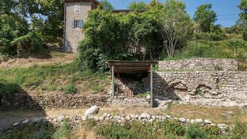 Un edificio de piedra con una estructura de madera en primer plano, rodeado de follaje y árboles.