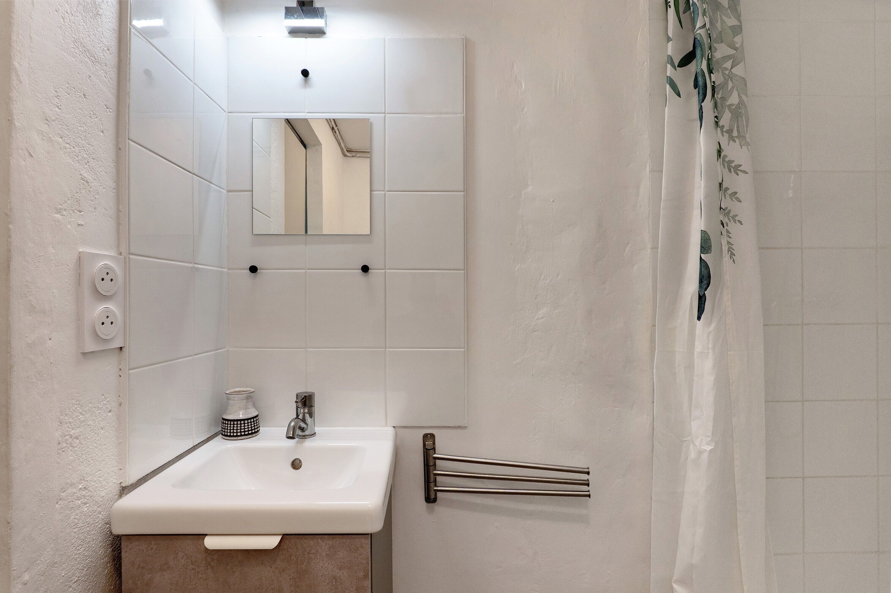 Een badkamer met een wit wastafelmeubel, spiegel en handdoekhouder.