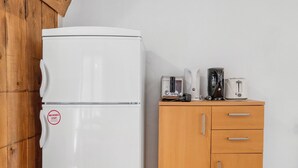 Un réfrigérateur blanc orné d’un autocollant indiquant « ANTI-MICROBES », un meuble en bois avec des tiroirs et un grille-pain posé sur le dessus.