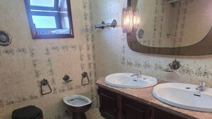 Ein Badezimmer mit zwei Waschbecken, einer Toilette, einem Bidet, einem Fenster und einem Spiegel.