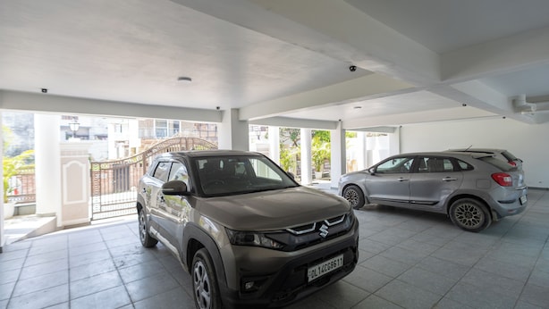 Un concesionario de autos con dos vehículos exhibidos, una zona techada y vistas a una zona residencial.