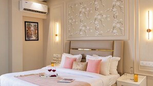 Habitación de hotel con cama, mesitas de noche, unidad de aire acondicionado, una obra de arte en la pared y un cuadro enmarcado.