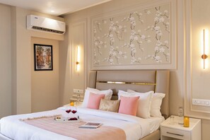 Ein Hotelzimmer mit einem Bett, Nachttischen, einer Klimaanlage, einem Wandbild und einem gerahmten Bild.
