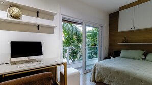 A bedroom with a bed, a desk with a computer, a chair, and a window with a view of greenery. - Casa Serena | Oceanfront, Heated Pool, Jacuzzi & Fireplace (Florianópolis)