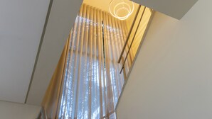 A room with a modern ceiling design, a visible window with curtains, and a light fixture. - Casa Serena | Oceanfront, Heated Pool, Jacuzzi & Fireplace (Florianópolis)