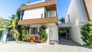 A modern two-story house with a flat roof, large windows, and a paved driveway. - Casa Serena | Oceanfront, Heated Pool, Jacuzzi & Fireplace (Florianópolis)