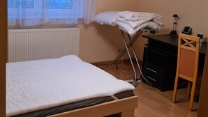 A bedroom with a bed, a radiator, a desk, and a chair.