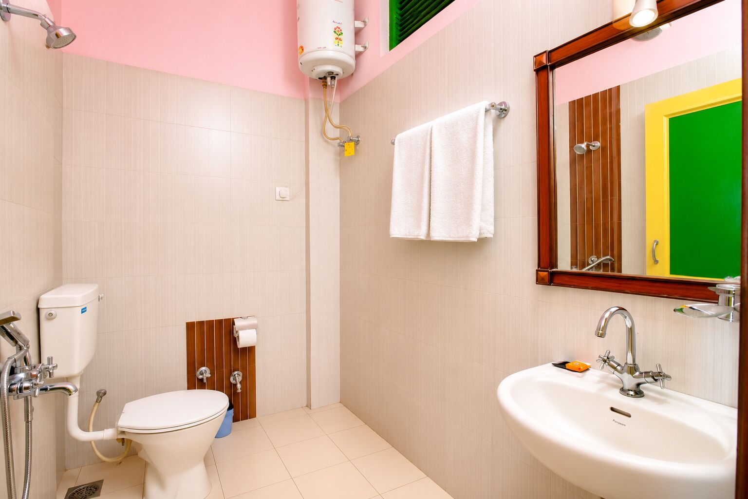 Un baño con inodoro, bidé, ducha, lavamanos y un espejo con reflejo de una puerta verde.