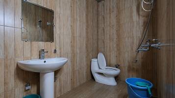 A bathroom with a wooden wall panel, a white sink, a toilet, and a shower.