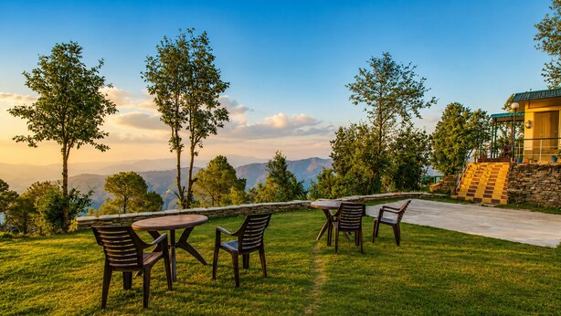 A patio with outdoor furniture, a stone wall, and a view of mountains.