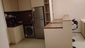 A compact kitchen with a washing machine, a refrigerator, and a small dining area.