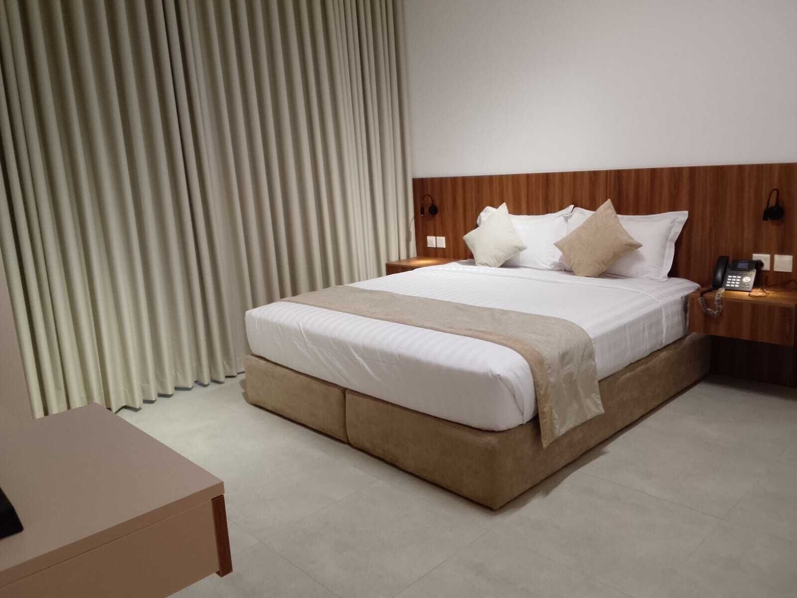 Una habitación de hotel con una cama grande, un teléfono en la mesita de noche y un cabecero de madera.