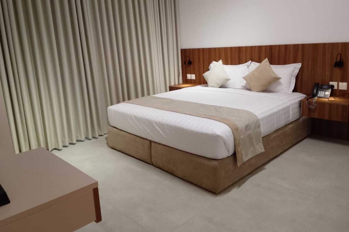 A hotel room with a large bed, a bedside phone, and a wooden headboard.