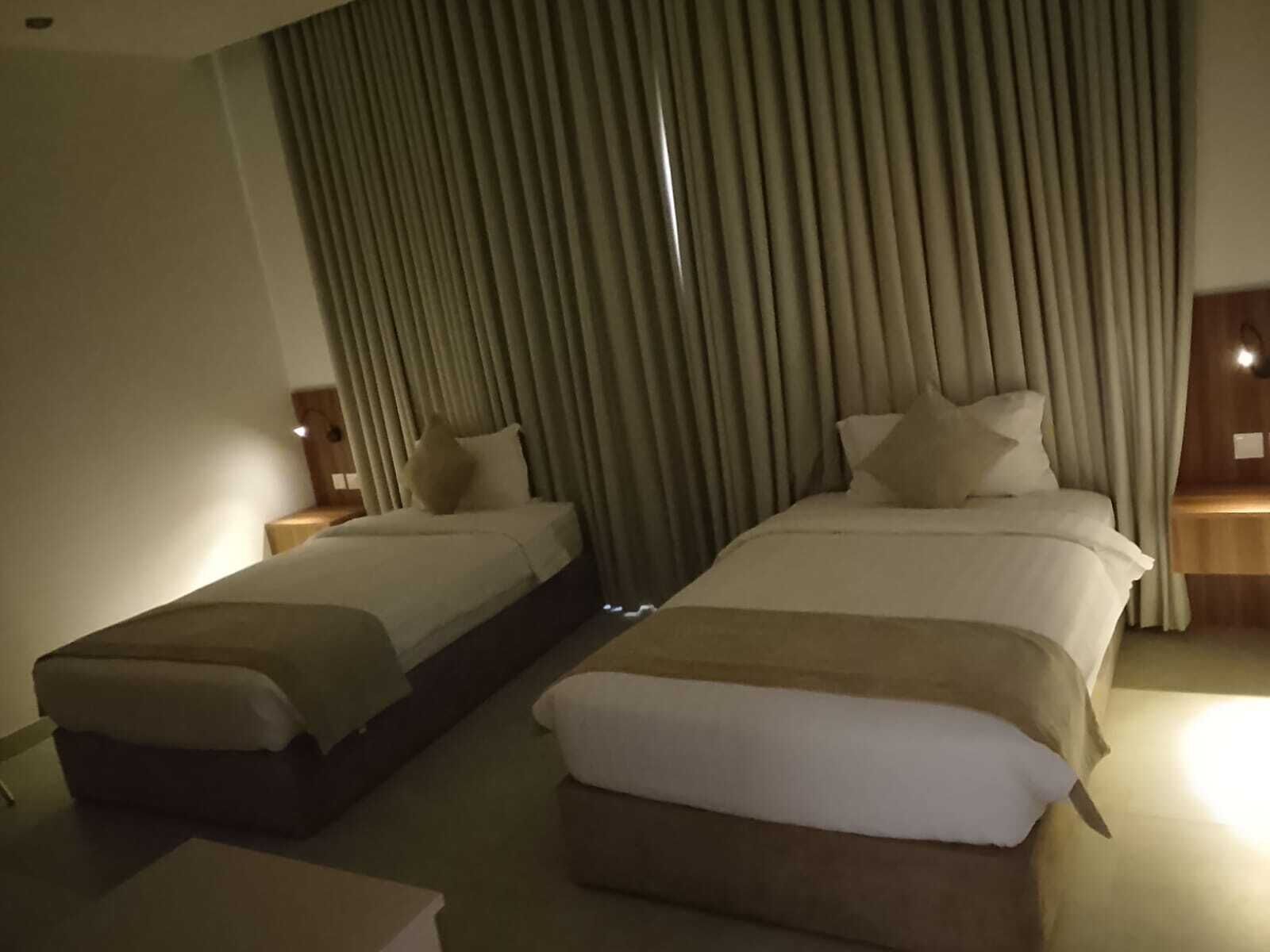 Habitación de hotel con dos camas, un sofá y una mesita.