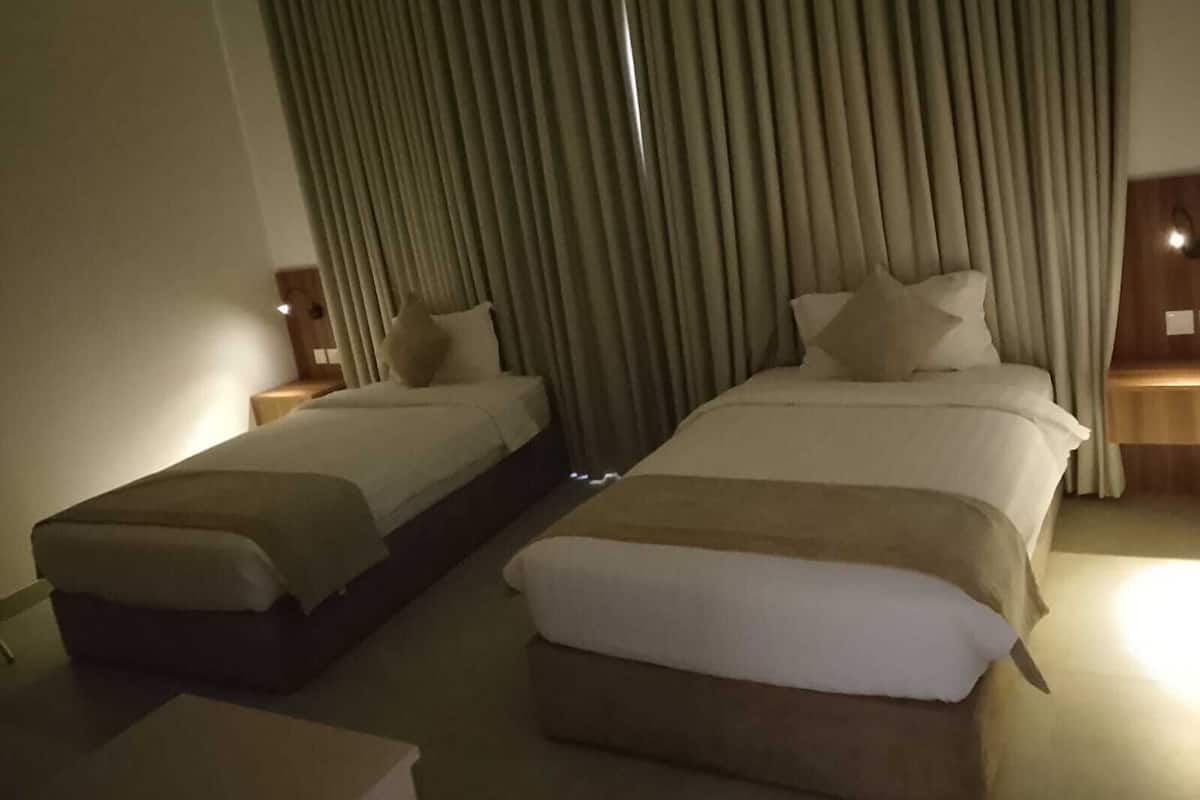 A hotel room with two beds, a sofa, and a small table.