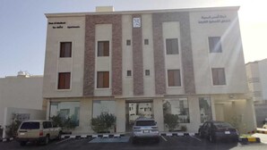 A multi-story building with a parking lot in front.