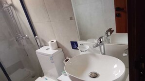 A bathroom with a toilet, a sink, and a shower.