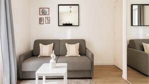 Una sala de estar moderna con un sofá gris, una mesa de centro blanca y obras de arte enmarcadas en la pared.