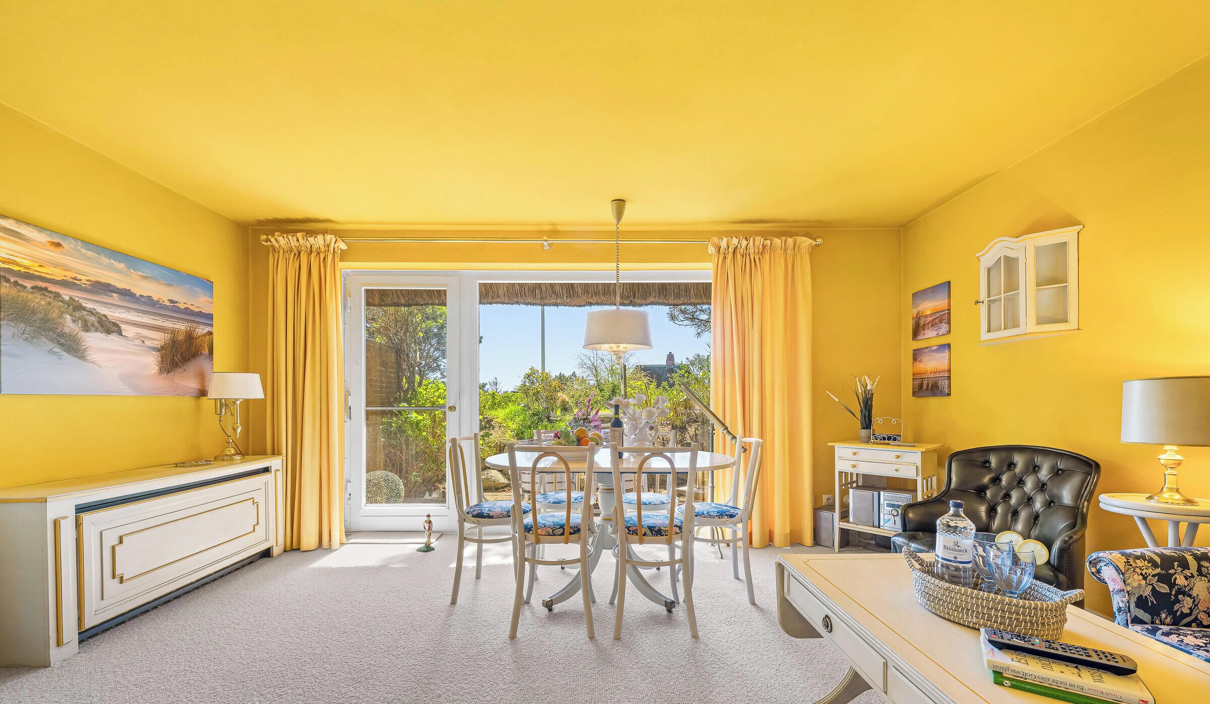 A room with a dining table, chairs, a sofa, a TV, and a window with curtains.