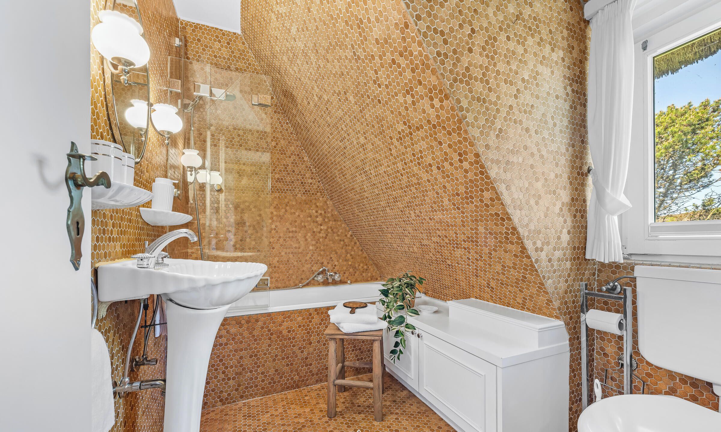 Een badkamer met een wand met honingraatmotief, een witte wastafel, een douche en een toilet.