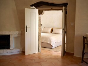Ein Zimmer mit Kamin, einem Bett mit weißer Bettwäsche und einer Tür zu einem anderen Raum.