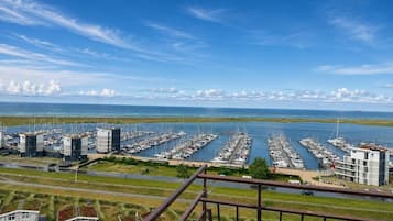 Uma marina com vários barcos atracados, céu claro e vista para o mar.