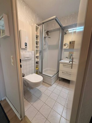 A modern bathroom with a shower, toilet, and vanity.