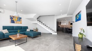 Ein modernes Wohnzimmer mit Sofa, Couchtisch und Treppe, die in einen Küchenbereich führt.