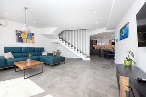 Un salon moderne avec un canapé, une table basse et un escalier menant à un espace cuisine.